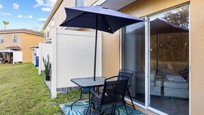 A patio with a table and chairs, a sliding glass door, and a white fence. - 2BR Townhome, Private, Monthly Stays Welcome! (Land O' Lakes)