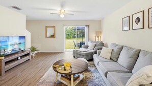 A living room with a TV, sofa, coffee table, and a ceiling fan. - 2BR Townhome, Private, Monthly Stays Welcome! (Land O' Lakes)