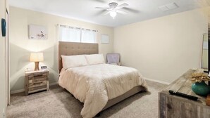 A bedroom with a bed, a nightstand, a lamp, a ceiling fan, and a dresser. - 2BR Townhome, Private, Monthly Stays Welcome! (Land O' Lakes)