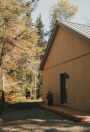 A wooden cabin with a sloped roof, a door, and a small porch area. - Scandinavian Chalet and Spa - Saint-Donat / Tremblant (Notre-Dame-de-la-Merci)