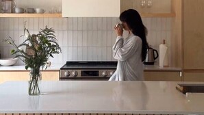 Una cocina moderna con armarios de madera, una isla central, luces colgantes y un florero con plantas.