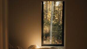 Un dormitorio con una cama, una ventana y vistas a árboles.