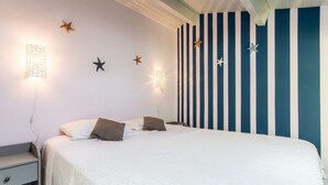 Een slaapkamer met een bed, nachtkastje, wandlampen, sterrenornamenten en een gestreepte wand.