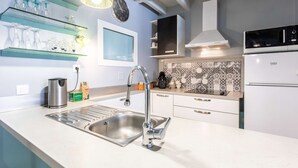 Een moderne keuken met een RVS-spoelbak, waterkoker, magnetron en koelkast.