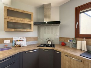 Eine moderne Küche mit Holzschränken, einem Gasherd, einem Wasserkocher und einem Kalender an der Wand.