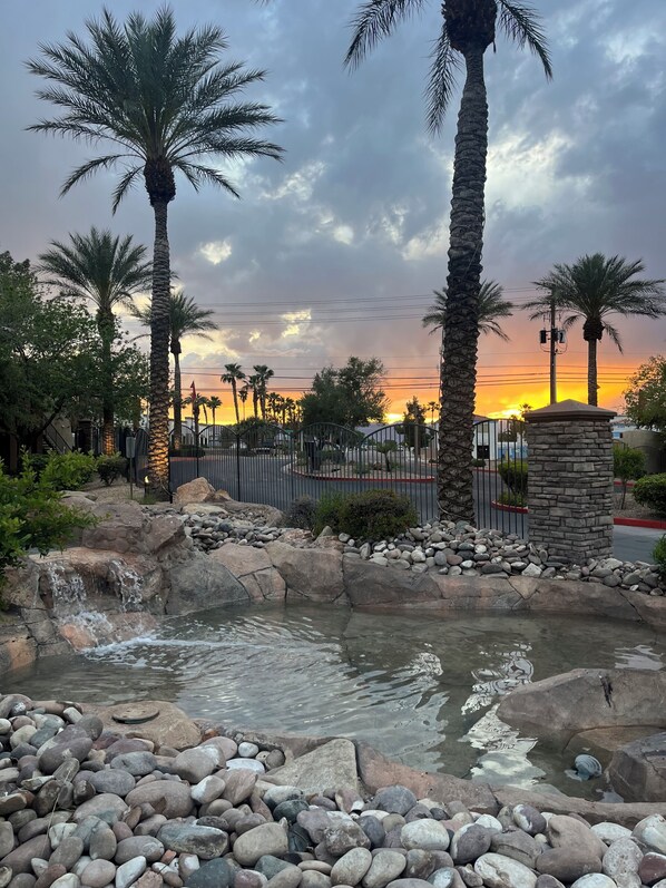 A landscaped area with palm trees, a water feature, and a stone wall. - Spacious condo with UNREAL views near Strip with all the amenities!!! (Las Vegas)