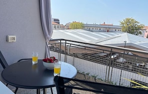 Un balcon avec une table, une boisson et des fruits.