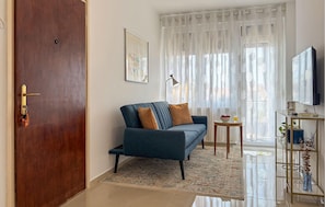 A living room with a sofa, a coffee table, a TV, and a door.