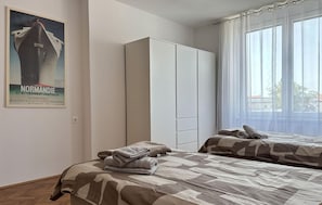 Une chambre d’hôtel avec deux lits, une armoire et une affiche au mur.