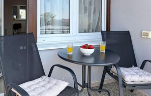 A small outdoor seating area with two chairs, a round table, a bowl of strawberries, and two glasses of orange juice.