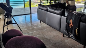 A modern living room with a large sofa, a telescope, and a view of the ocean.