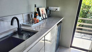 A kitchen with a sink, a gas stove, a marble countertop, a framed picture, and a power outlet.