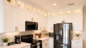 A modern kitchen with white cabinets, stainless steel appliances, and a coffee bar. - Lakefront Oasis w/covered Patio + outdoor Kitchen (Fort Worth)