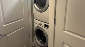 Un lavadero con dos lavadoras apiladas, una puerta y una pared.