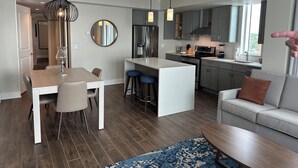 Una cocina moderna con una isla central, taburetes de bar y una mesa de comedor con sillas.