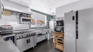 A kitchen with a stove, oven, microwave, refrigerator, and a wine rack. - Mallow View Guest House | Cleethorpes Beachside (Cleethorpes-Mallow View Guest House)