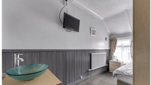 A hotel room with a glass bowl sink, a flat-screen TV, a radiator, a bed, and a window with curtains. - Mallow View Guest House | Cleethorpes Beachside (Cleethorpes-Mallow View Guest House)