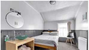 A bedroom with a bed, a bedside table with a bowl, a chair, a window, and a radiator. - Mallow View Guest House | Cleethorpes Beachside (Cleethorpes-Mallow View Guest House)