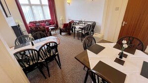 A dining area with a table set for four, a sofa, and a window with curtains.