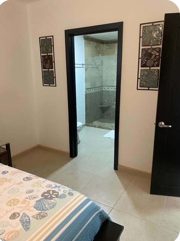 Une chambre à coucher comprenant un lit, une porte donnant sur une salle de bain et un mur orné de panneaux décoratifs.
