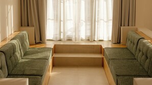 A modern living room with a sofa set, a coffee table, and a large window with sheer curtains. - Nangi Hotel Boutique (Valle de Guadalupe)