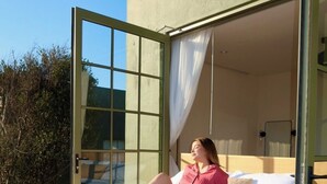 A bed with a white mattress, a wooden frame, and a person lying on it. - Nangi Hotel Boutique (Valle de Guadalupe)