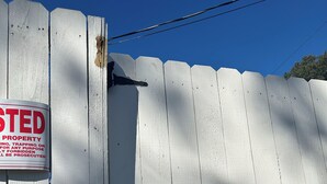 Una recinzione di legno bianco con un cartello che indica che la proprietà è privata e vietato l'accesso.