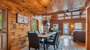 Een houten interieur met een eettafel, stoelen, een kroonluchter en een bordje met de tekst 'Welcome to Fox Creek Lodge'.