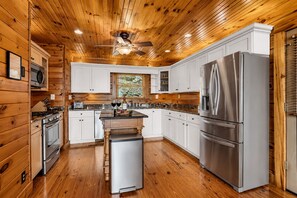 A kitchen with wooden walls, a stainless steel refrigerator, and a central island. - 11 Acres, Stunning Views, Near Cloudland Canyon (Menlo)