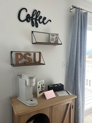 A coffee station with a coffee maker, a sign that says 'Coffee,' a shelf with a mug saying 'I like my coffee hot,' and a welcome sign. - The Nittany House in Bellfonte (Bellefonte)