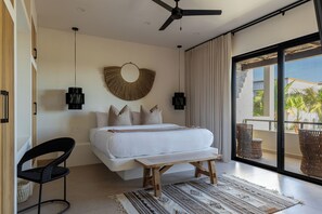 Ein Schlafzimmer mit Bett, Deckenventilator, großem Fenster und Blick ins Freie.