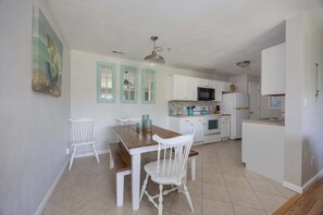 A kitchen with white cabinets, a wooden table, and a white chair. - 1501 - Carolina Breeze, Top-Floor 2BR Monteray Pines: Screened Balcony (Corolla)