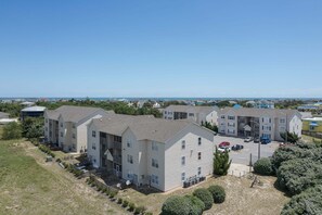 A residential complex with multiple apartment buildings, a parking area, and a view of the sea. - 1501 - Carolina Breeze, Top-Floor 2BR Monteray Pines: Screened Balcony (Corolla)