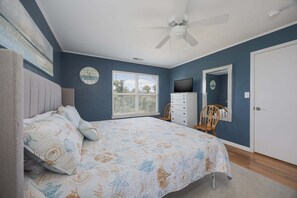 A bedroom with a bed, a ceiling fan, a dresser, a television, a window, and a door. - 1501 - Carolina Breeze, Top-Floor 2BR Monteray Pines: Screened Balcony (Corolla)