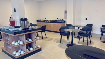 Um saguão moderno de hotel com um espaço para café, área de estar e um balcão.