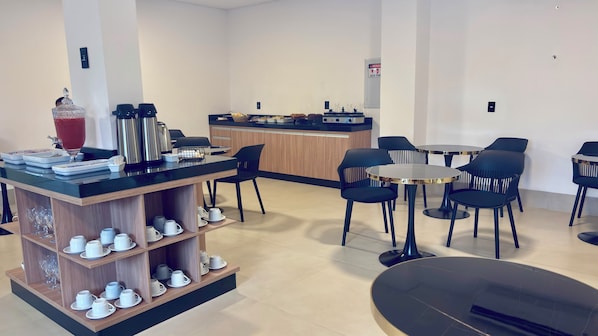 Eine moderne Hotellobby mit einer Kaffeestation, Sitzgelegenheiten und einer Rezeption.
