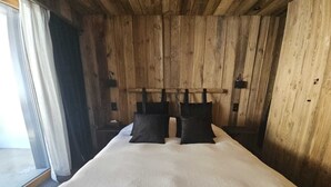 A wooden room with a bed, a window with curtains, and a wooden headboard. - Discover this superb 3.5-room premium apartment, completely renovated with quality materials, combin (Thyon-Les Collons)