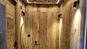 A wooden interior with a tiled floor, a central door, and wall-mounted lighting. - Discover this superb 3.5-room premium apartment, completely renovated with quality materials, combin (Thyon-Les Collons)