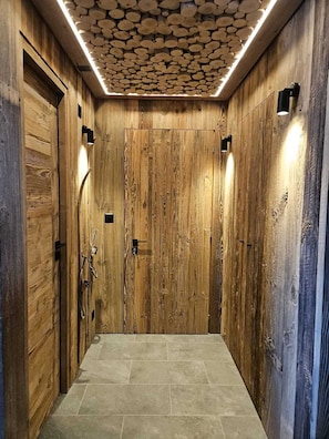 Un interno in legno con pavimento piastrellato, una porta centrale e illuminazione a parete.