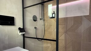 Une salle de bain moderne avec une douche à parois de verre, des toilettes et un porte-serviettes.