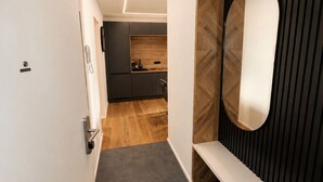Un couloir moderne avec un plancher en bois, un mur gris foncé et une porte blanche.