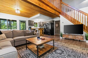 A spacious living room with a wooden ceiling, a large sofa, a coffee table, and a TV. - New Listing! Family Friendly Hot Tub Cabin+Fire Pit+Dogs Friendly+Close to BR! (Blue Ridge)