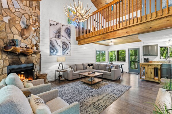 A spacious living room with a stone fireplace, a wooden ceiling, and a view of the kitchen. - New Listing! Family Friendly Hot Tub Cabin+Fire Pit+Dogs Friendly+Close to BR! (Blue Ridge)