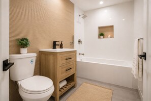 Une salle de bain moderne équipée de toilettes, d’un meuble-lavabo en bois, d’un lavabo et d’une baignoire.