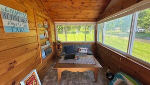 L’intérieur chaleureux d’un chalet avec des murs en bois, un canapé, une table basse et une vue sur un paysage verdoyant.