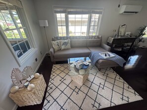 A living room with a sofa, a glass coffee table, a patterned rug, and a decorative wall piece. - Diamond Lake Hideaway (Cassopolis)