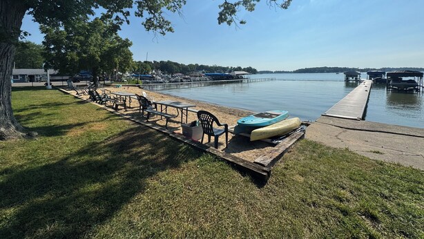 Un parc au bord du lac, équipé de tables de pique-nique, d’un canoë et d’une jetée qui s’avance dans l’eau.