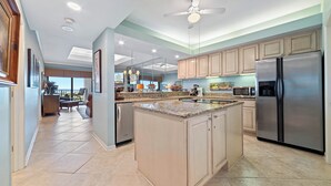 Una cocina amplia con una isla central, electrodomésticos de acero inoxidable y un ventilador de techo.