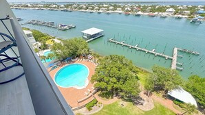Una piscina, zona verde y vista a un puerto deportivo con barcos.