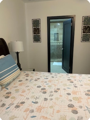 Un dormitorio con cama, mesita de noche, lámpara y puerta que da a un balcón.